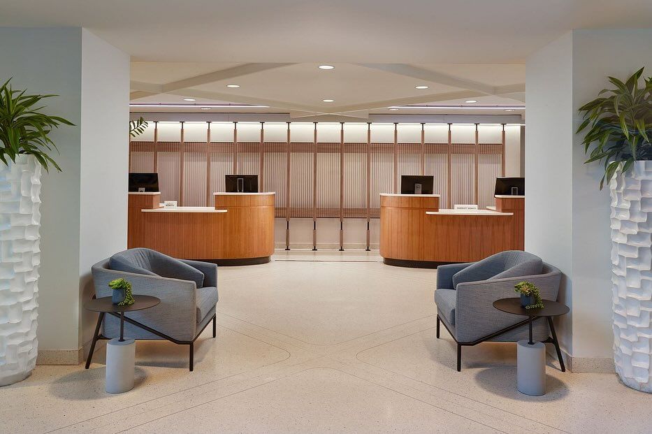 A hotel lobby with two chairs and two desks.