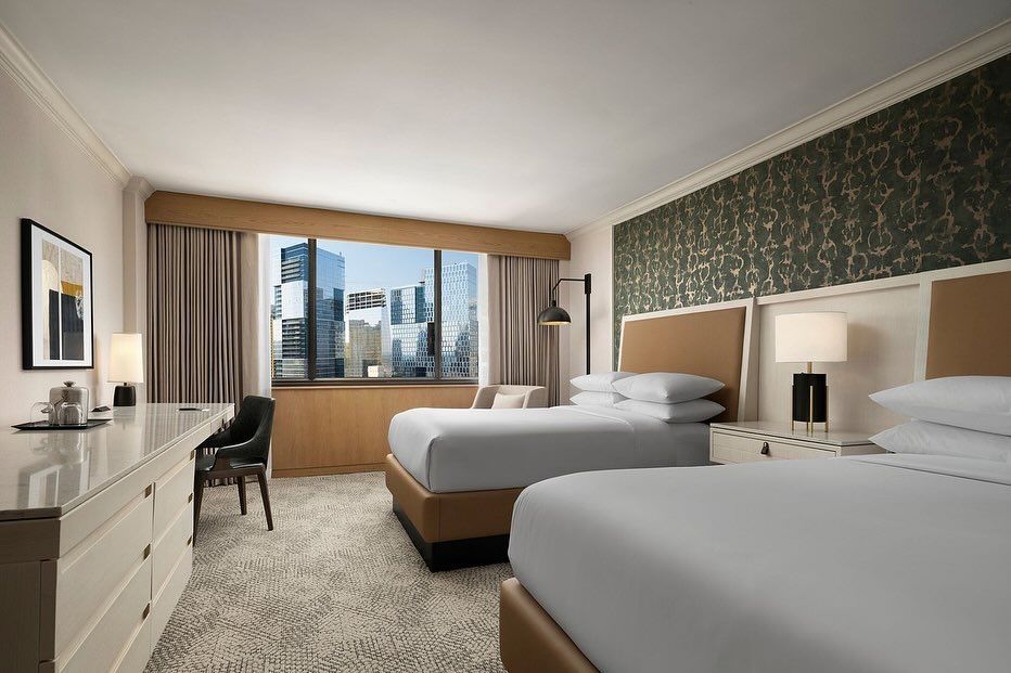 A hotel room with two beds and a large window