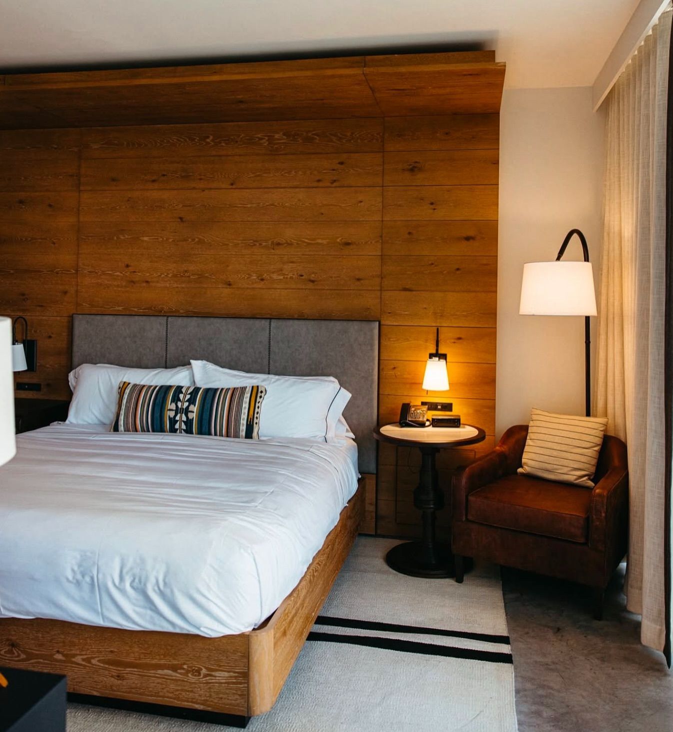 A hotel room with a king size bed and a chair