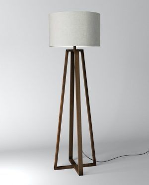 A wooden floor lamp with a white shade on a white surface.