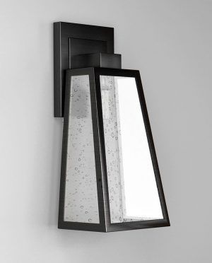 A black wall light with a clear glass shade on a white wall.