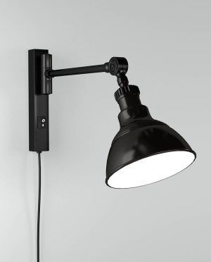 A black wall light with a white shade is hanging on a white wall.