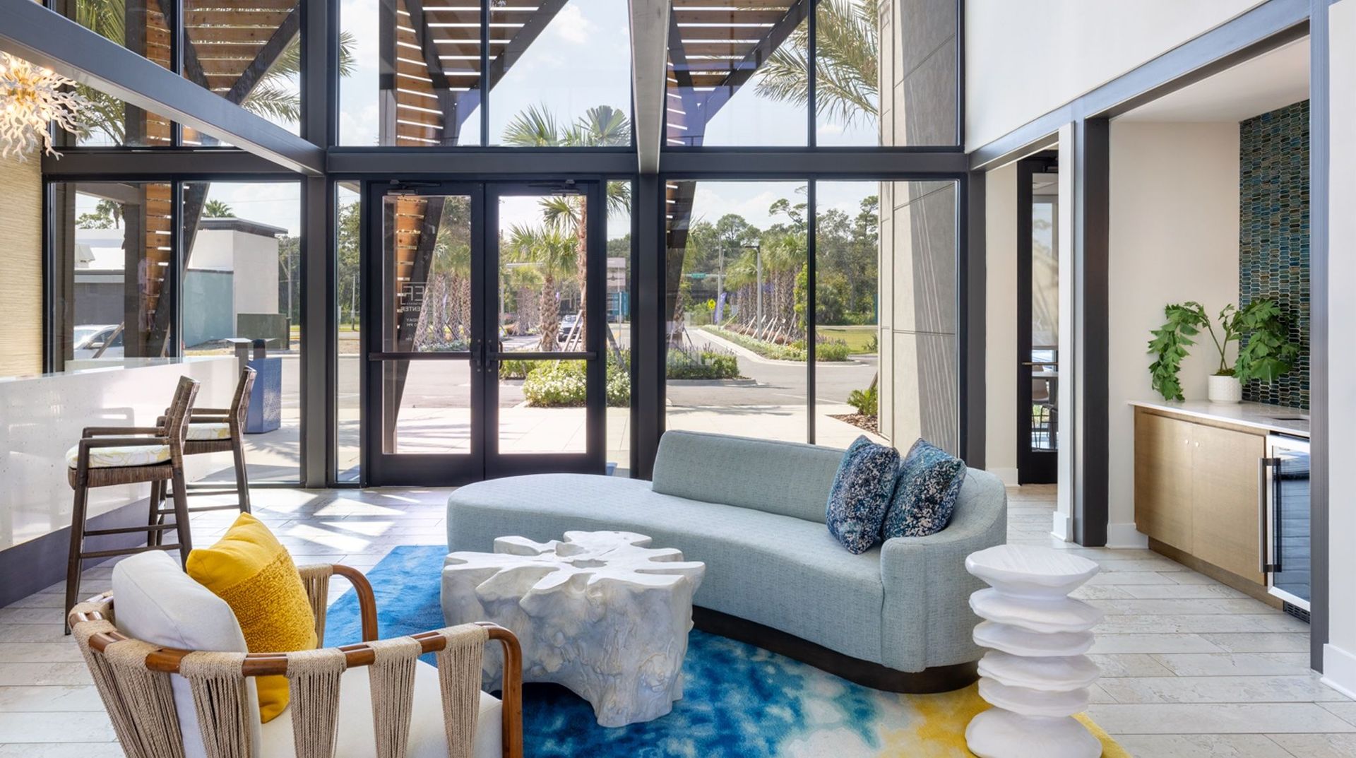 A living room with a couch , table , chairs and a large window.