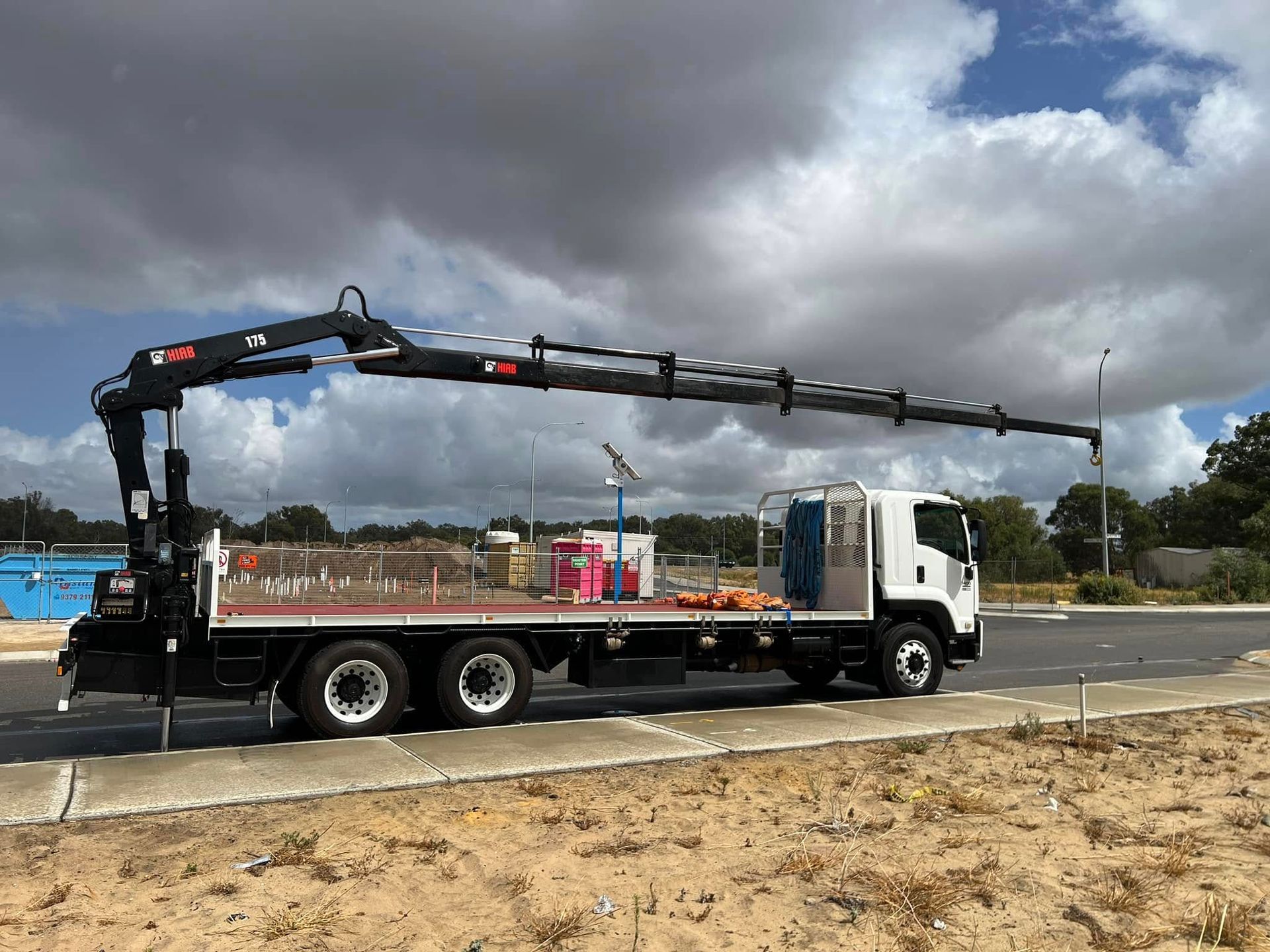 A truck with a crane on the back is parked on the side of the road.