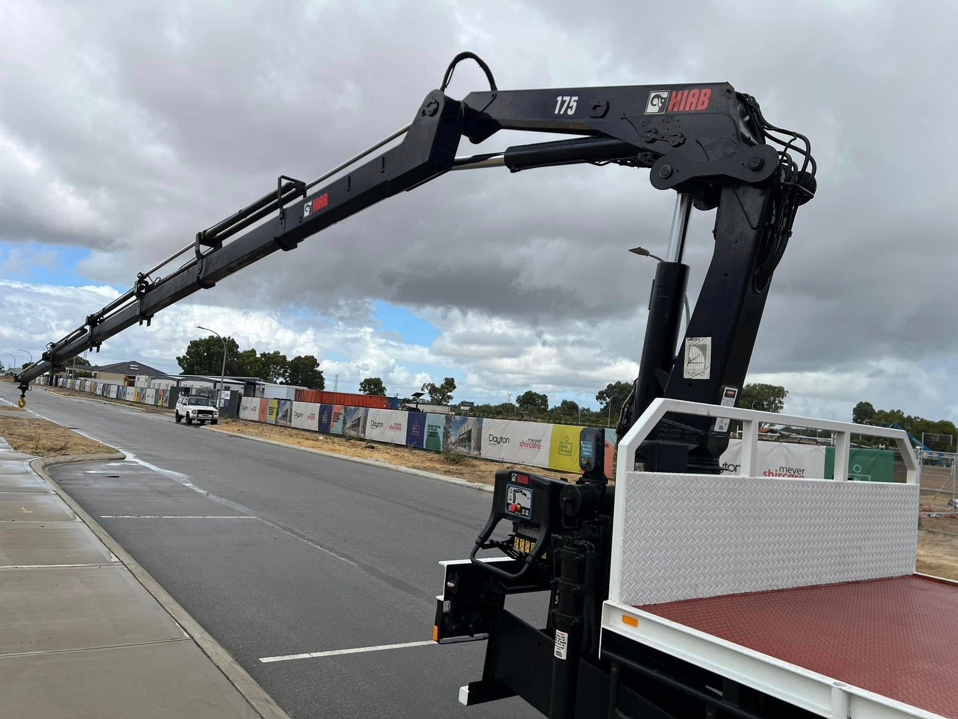 A truck with a crane attached to it is parked on the side of the road.