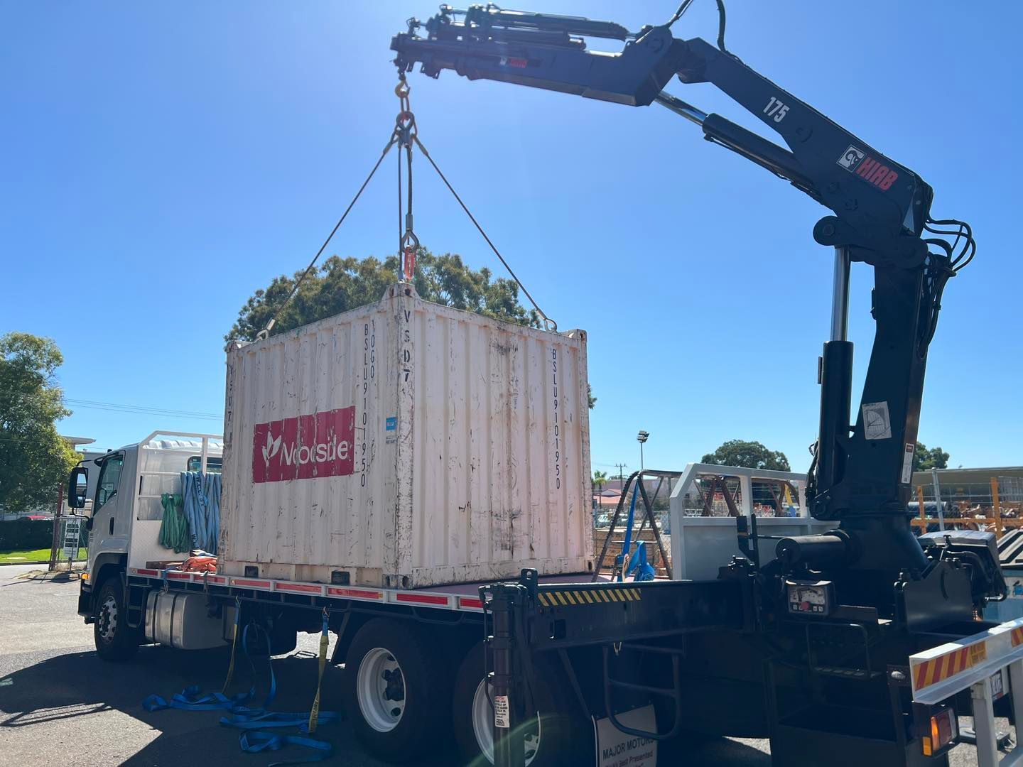 A crane is lifting a shipping container on top of a truck.