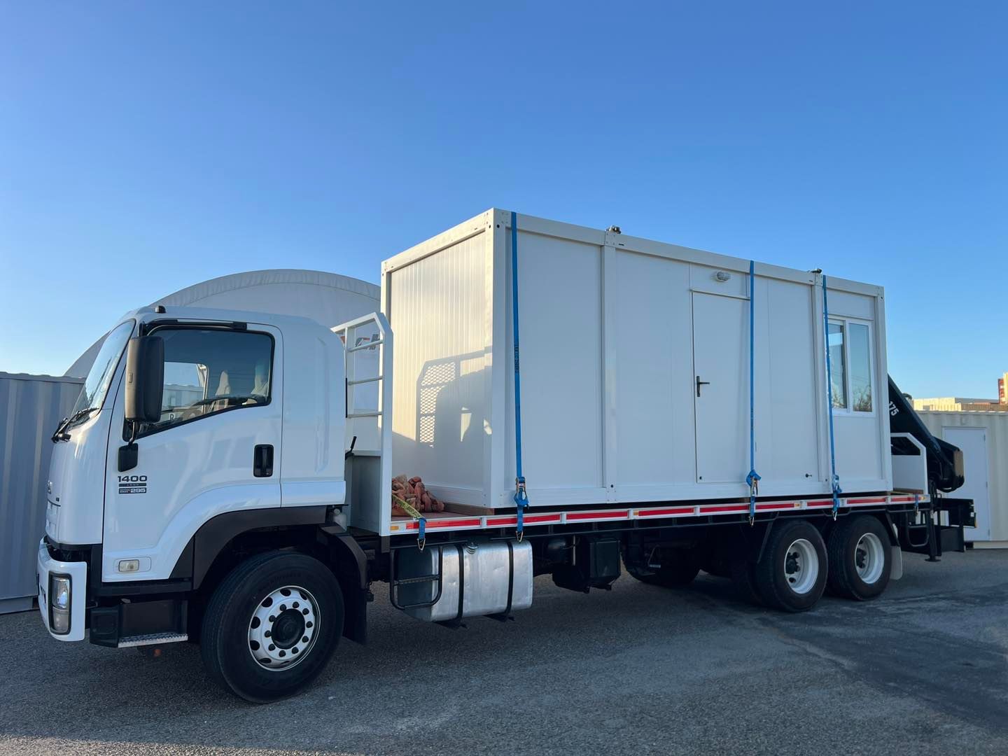 A white truck with a container on the back is parked in a parking lot.