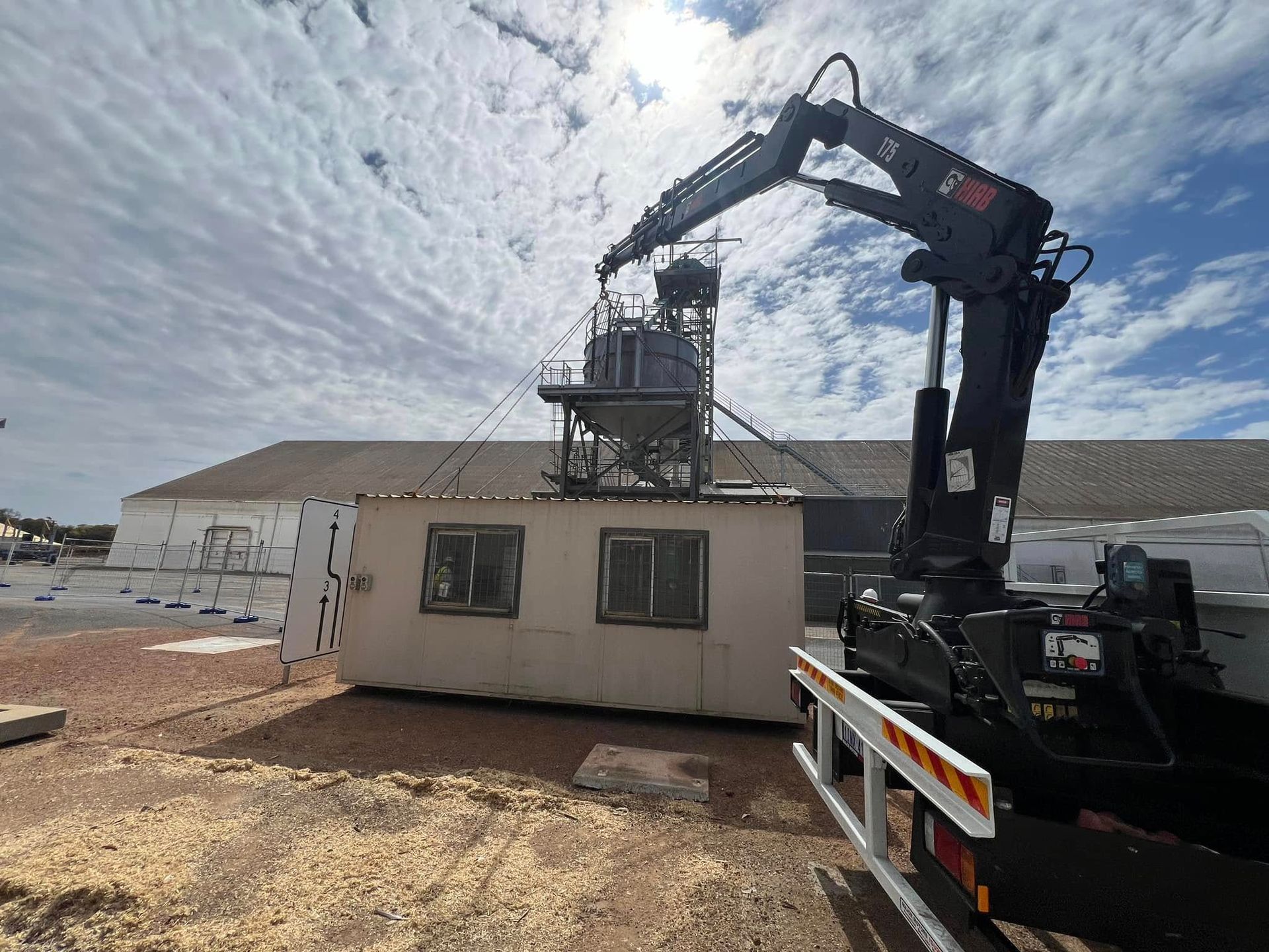 A crane is lifting a building in front of a building.