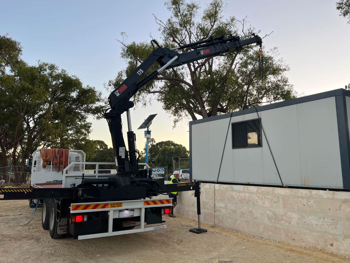 A truck with a crane attached to it is carrying a container.