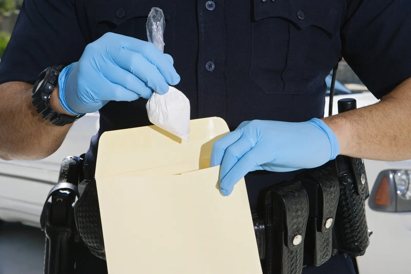 A police officer filing a bag of drugs, representing the topic of drug crimes in criminal defense law.