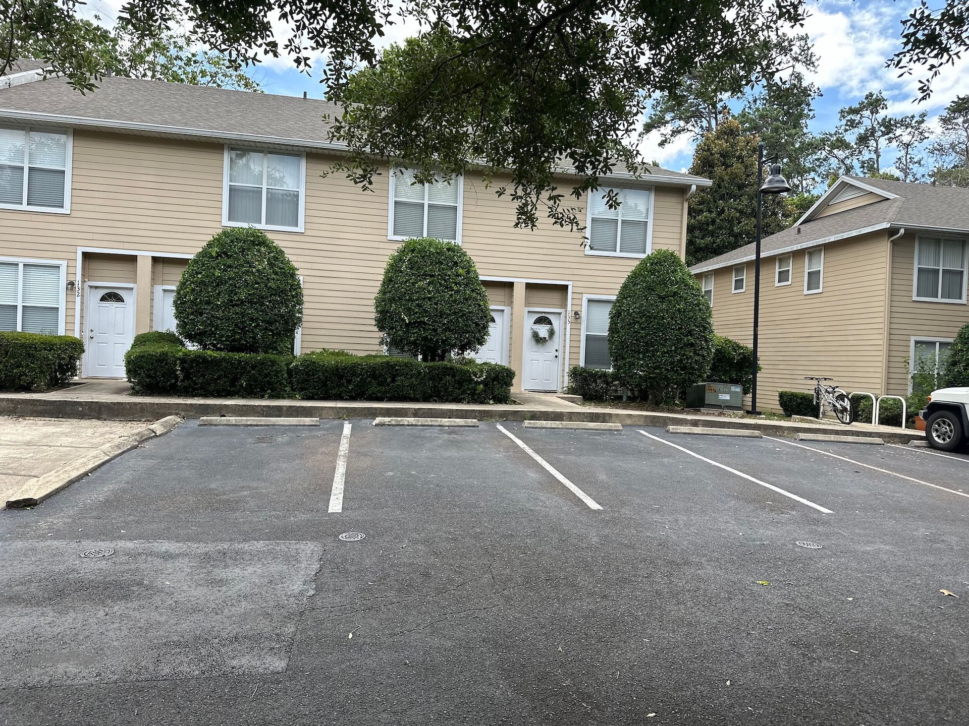 A car is parked in front of a building with a parking lot in front of it.