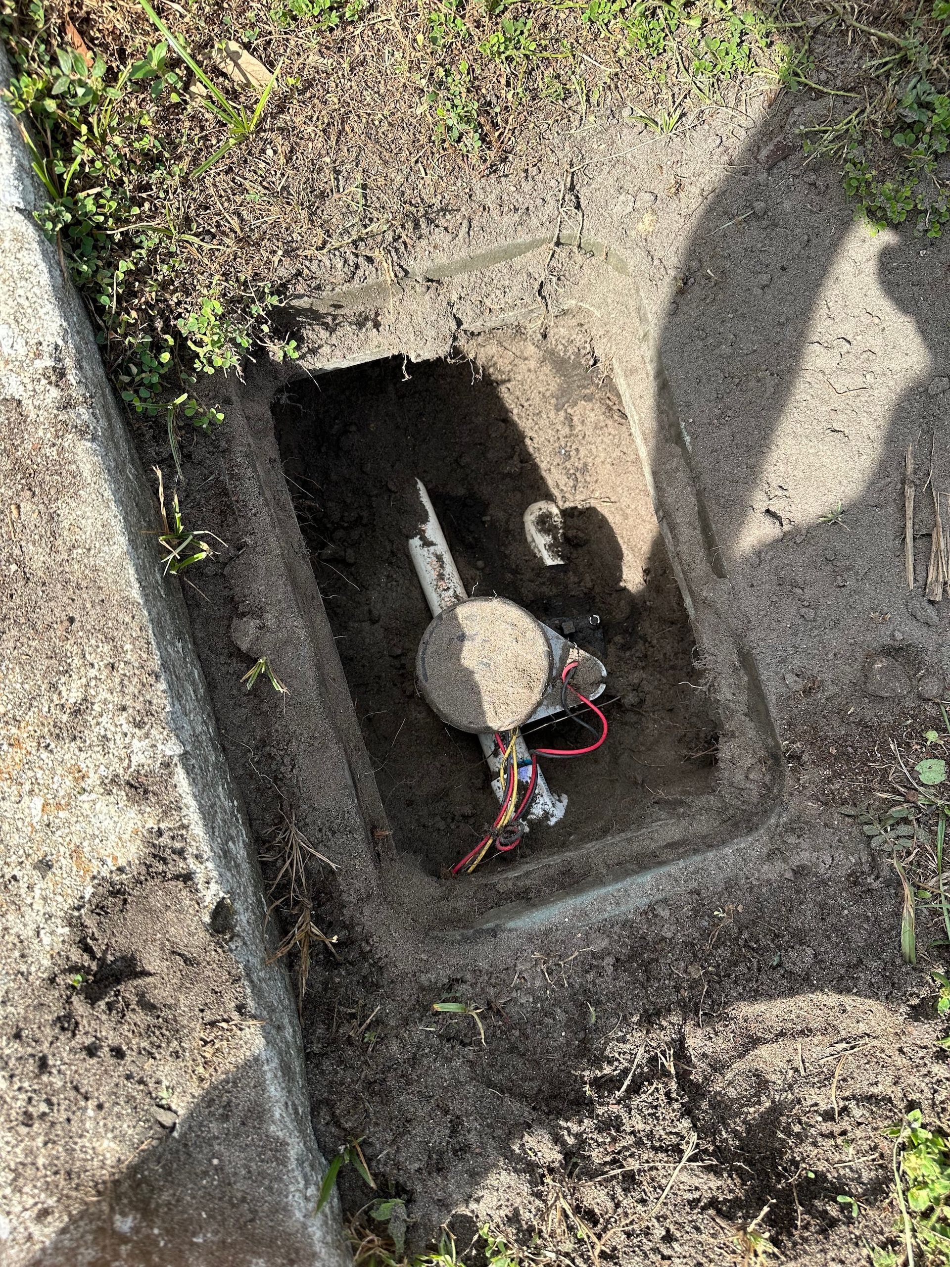 A water meter is sitting in a hole in the ground.
