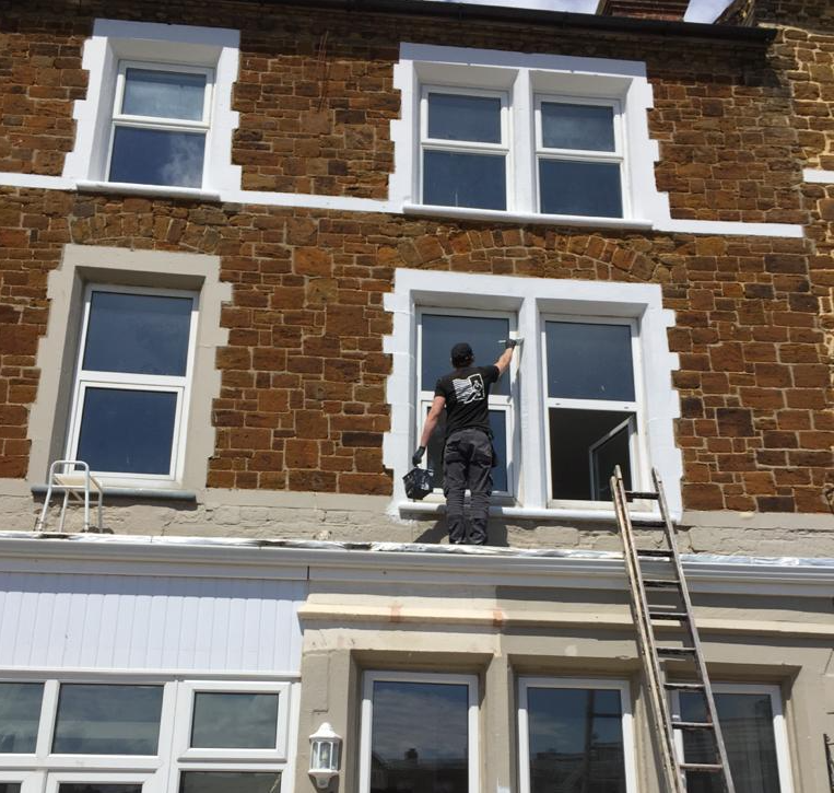 Image showing director of ABS Plastering working at height re-painting external window surround of period property