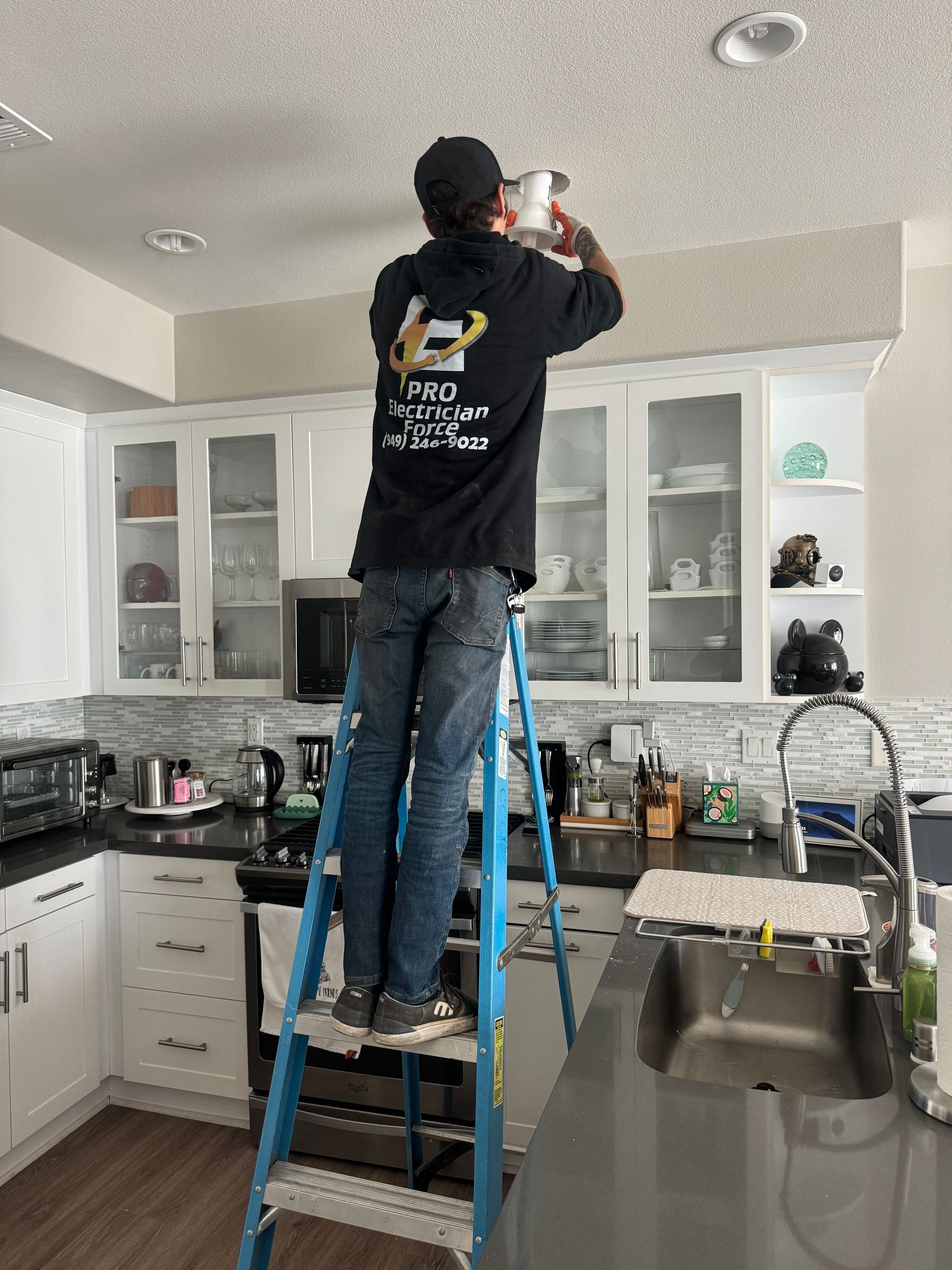 A man is standing on a ladder in a kitchen.