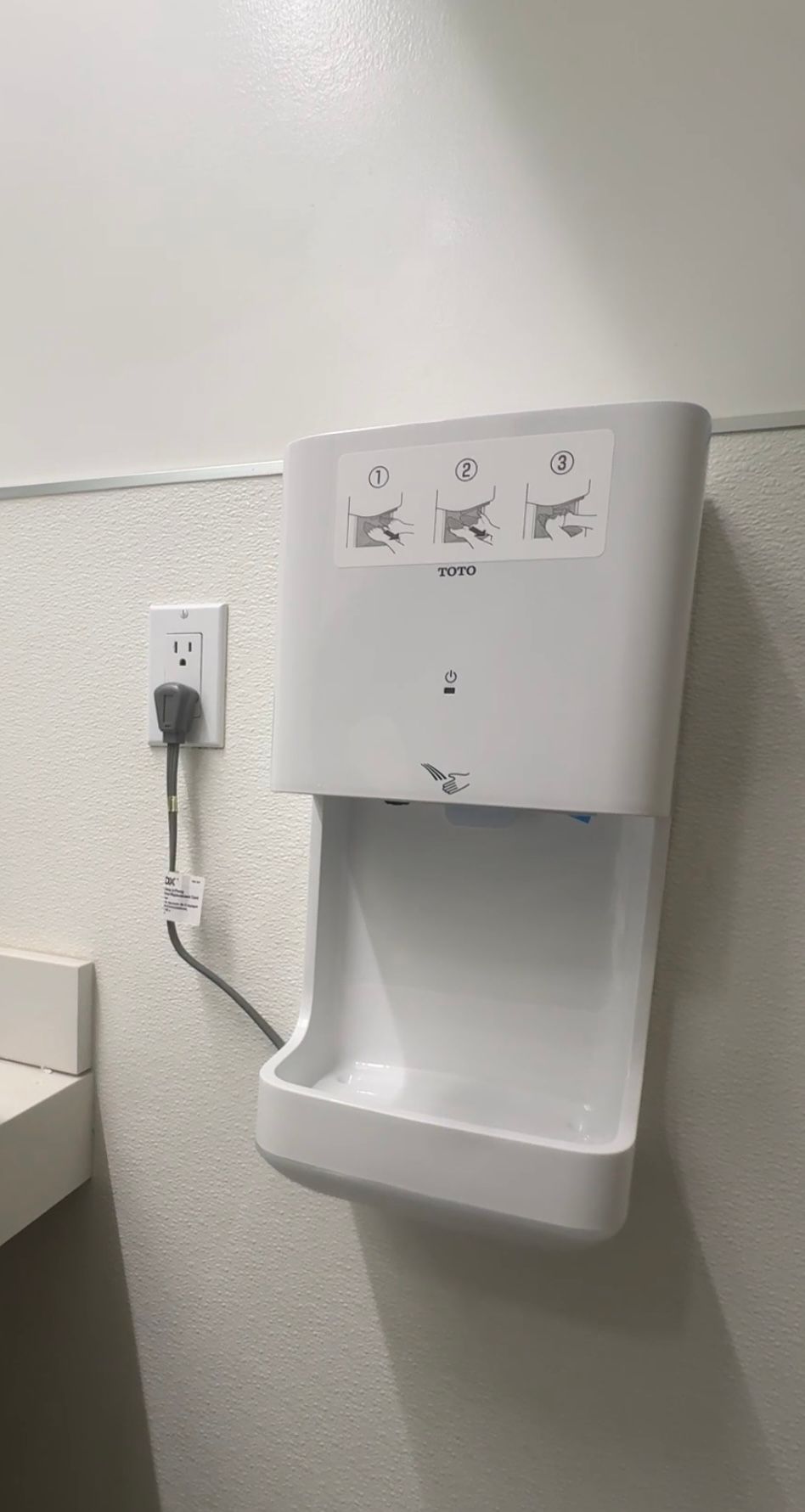 A hand dryer is hanging on a wall in a bathroom.