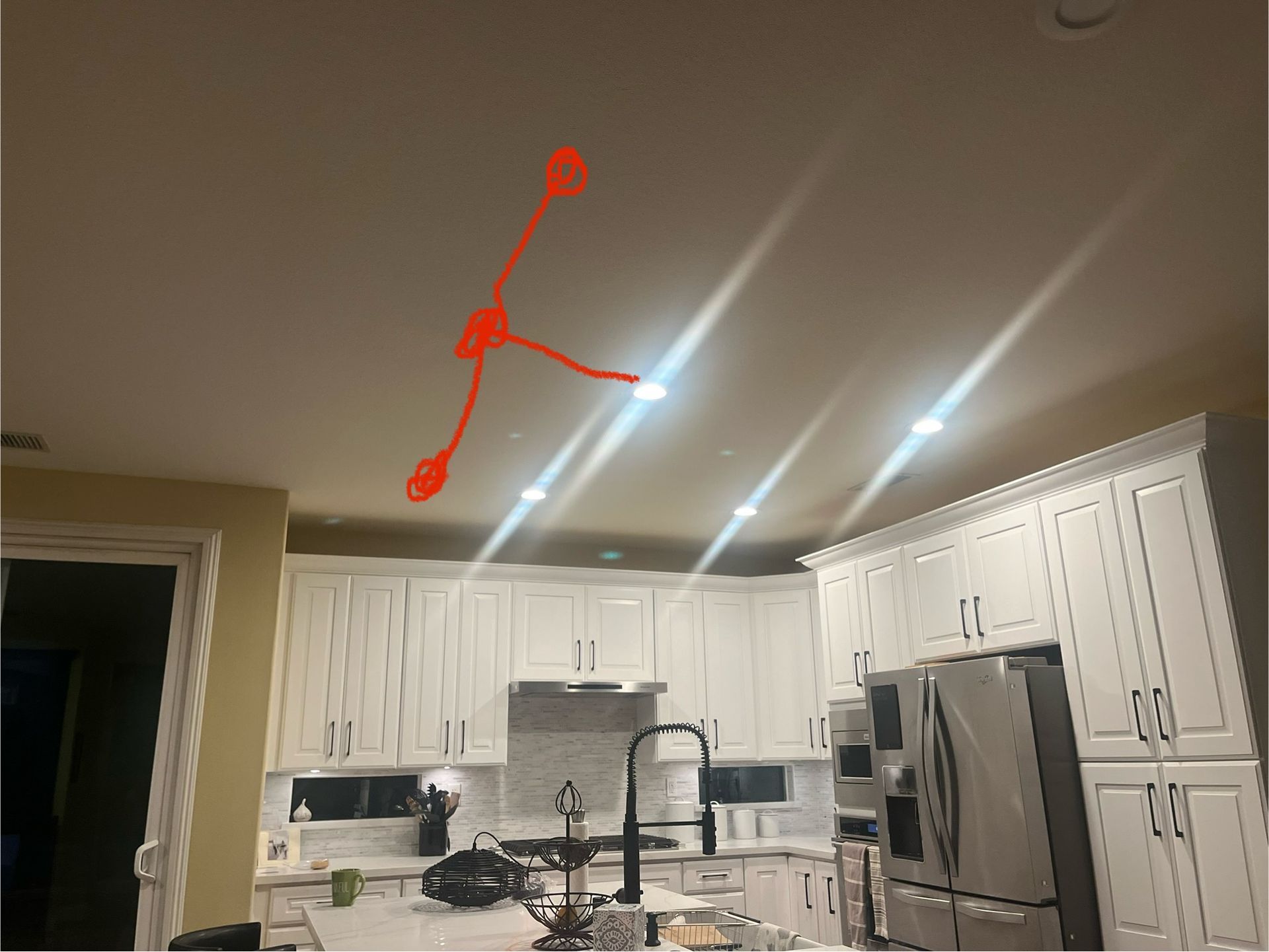 A kitchen with white cabinets and a clock on the ceiling