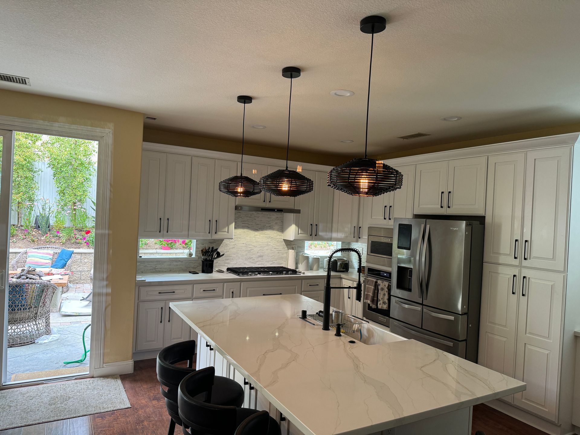 A kitchen with white cabinets , stainless steel appliances and a large island.