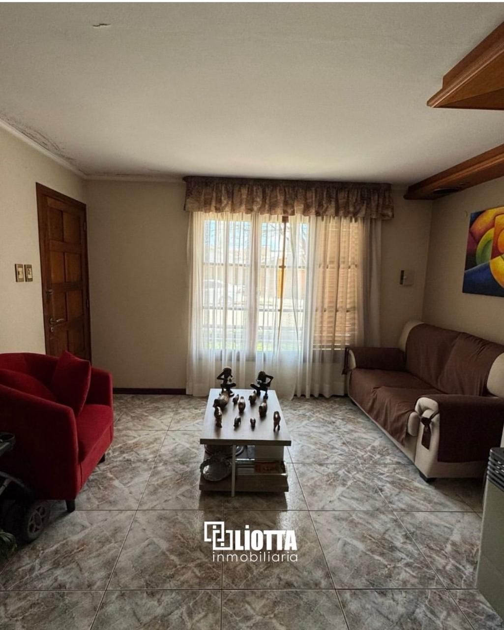 Exterior de casa con fachada de ladrillo, puerta de garaje de madera y un coche blanco aparcado delante.