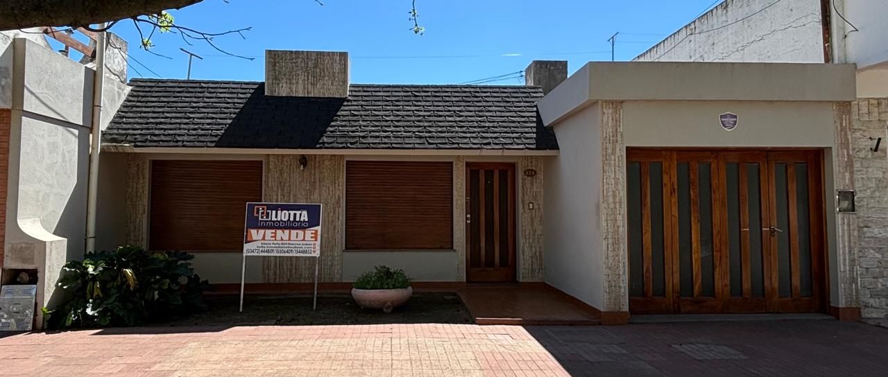 Una casa con puertas de madera, un garaje y un cartel de