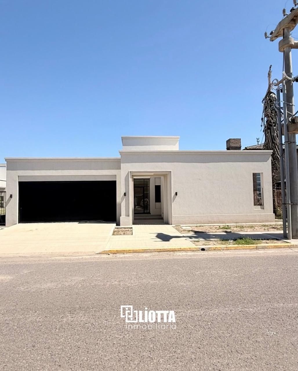 Casa moderna, blanca, con garaje y puerta de entrada, bajo un cielo azul claro.