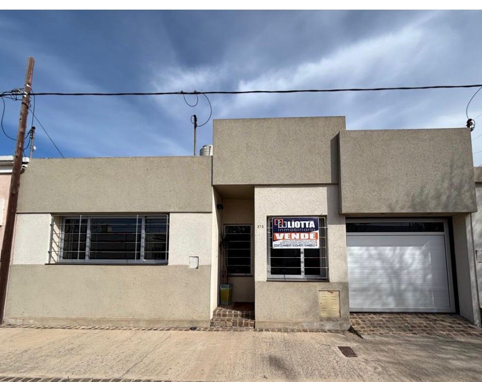 Una casa beige con un cartel de