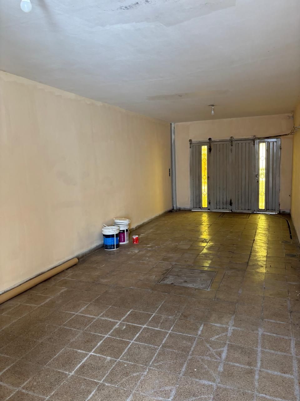 Edificio de ladrillo rojo con ventanas enrejadas, cartel de venta y árboles.