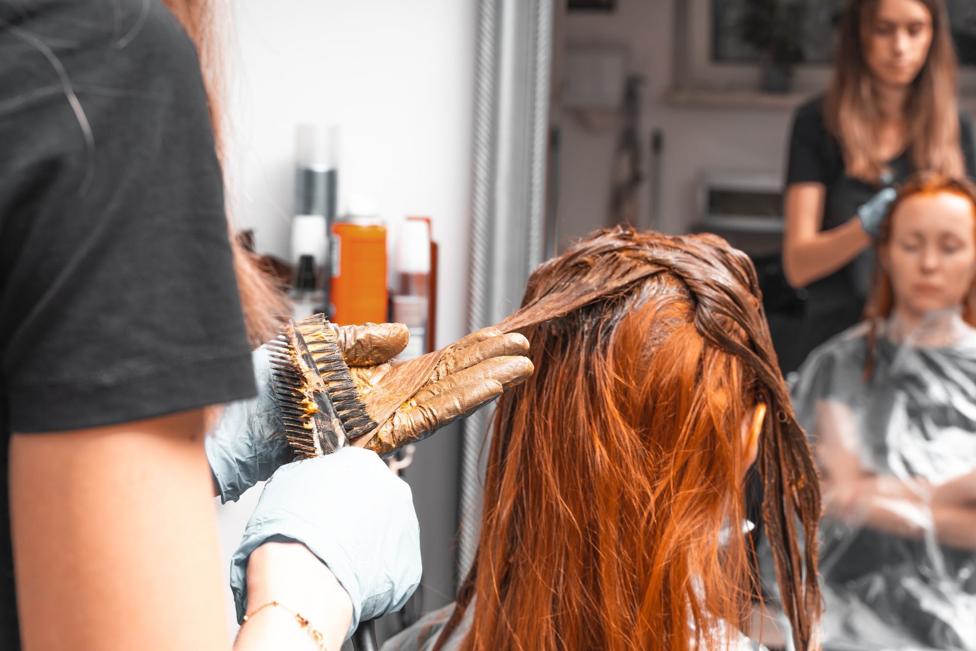 Hairdresser applying color to a client's hair in a salon.