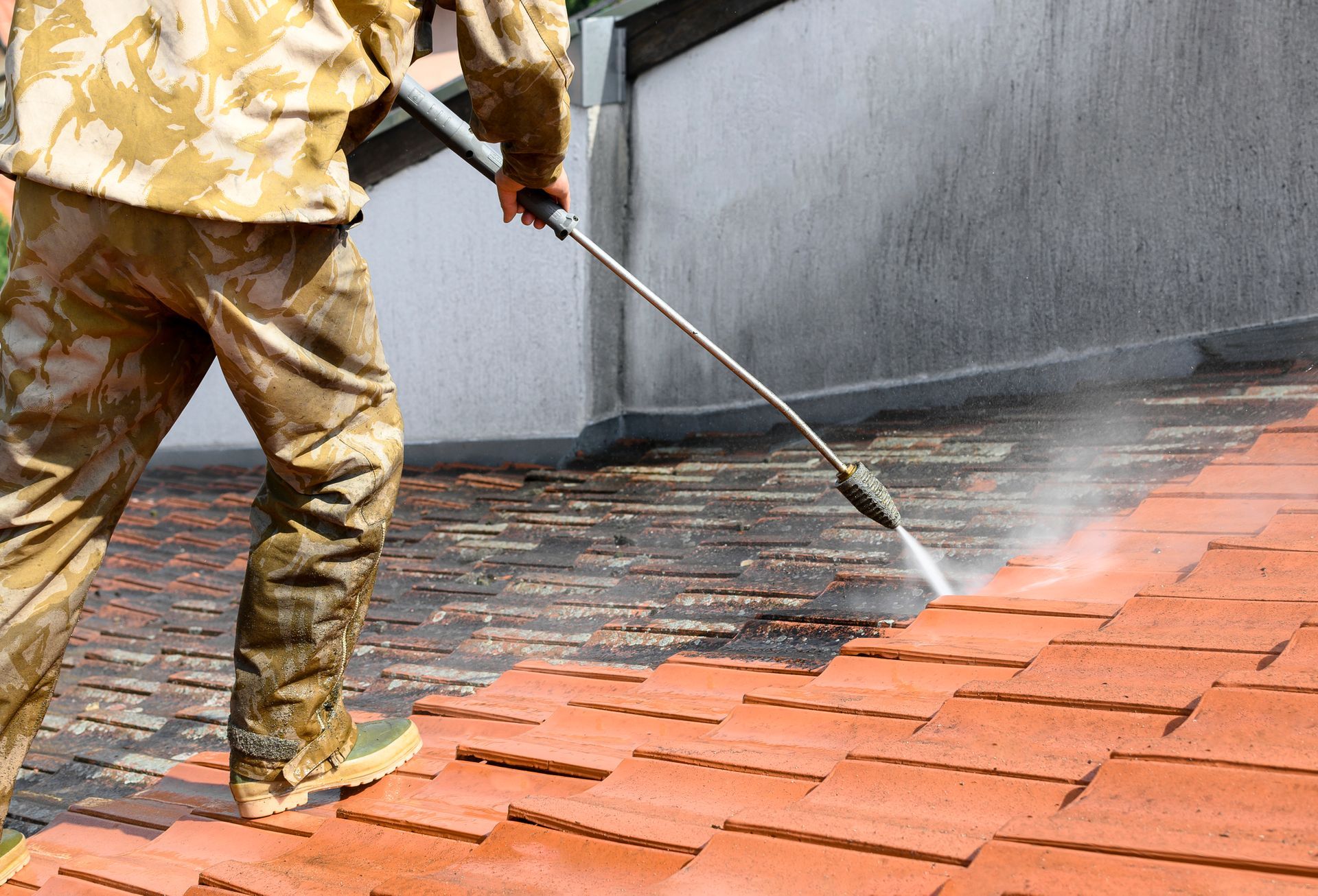A man is cleaning a brick patio with a high pressure washer.