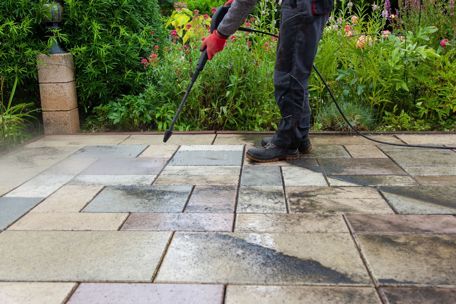 A man is cleaning a patio with a high pressure washer.