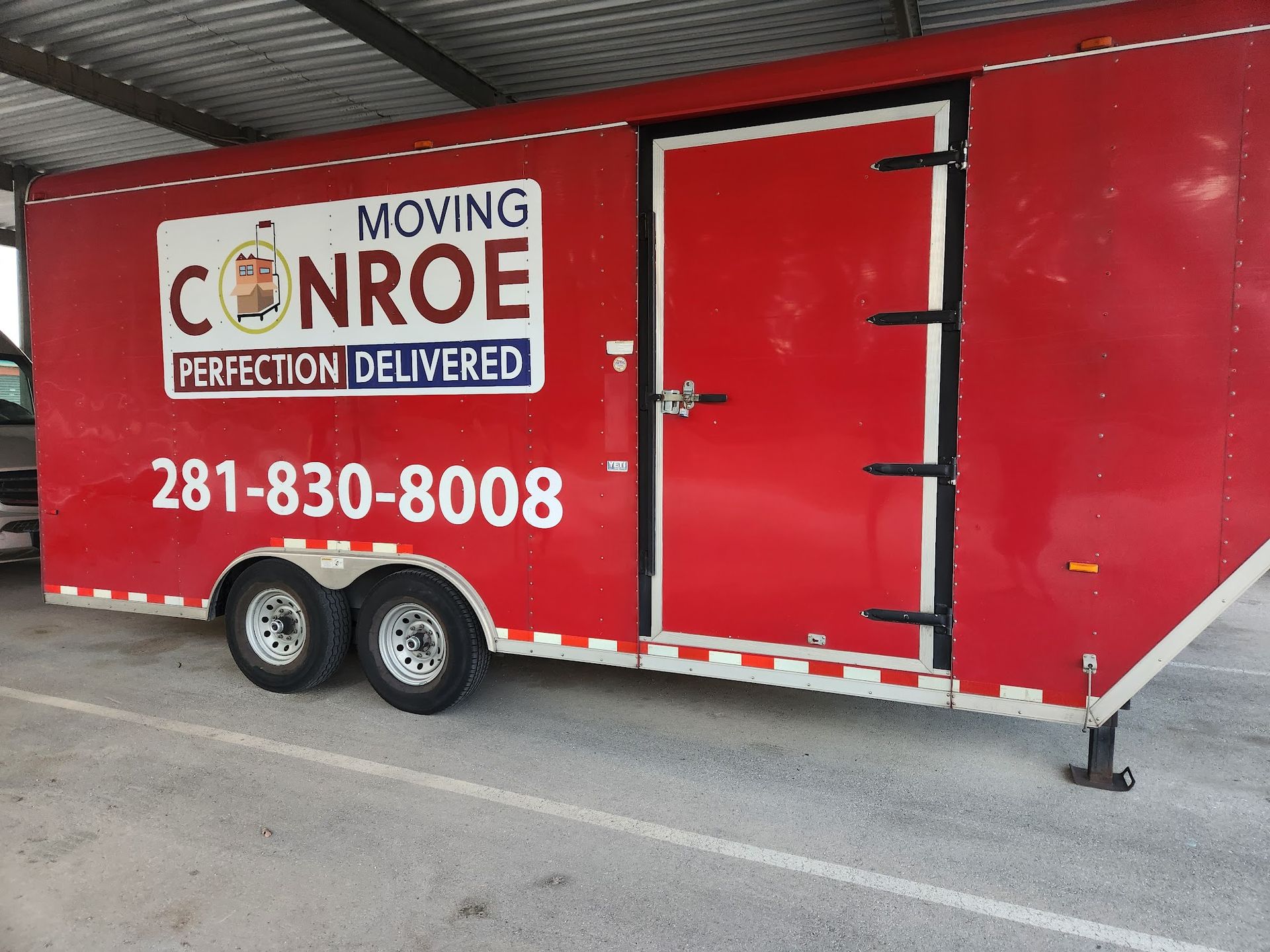 A red trailer that says moving conroe perfection delivered