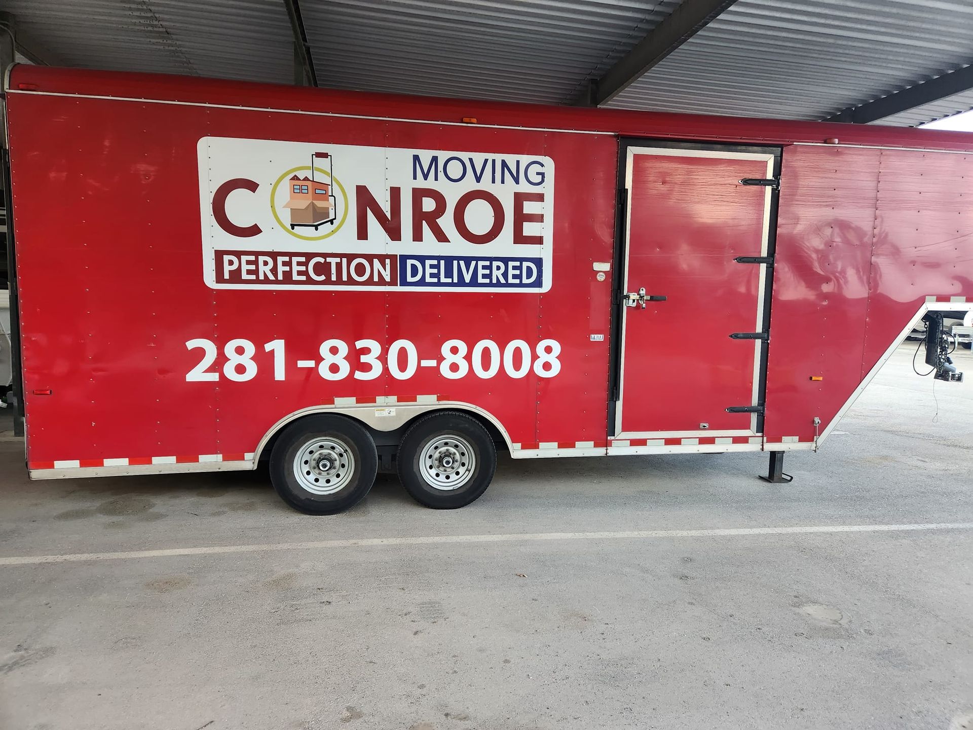 A red trailer that says moving conroe perfection delivered
