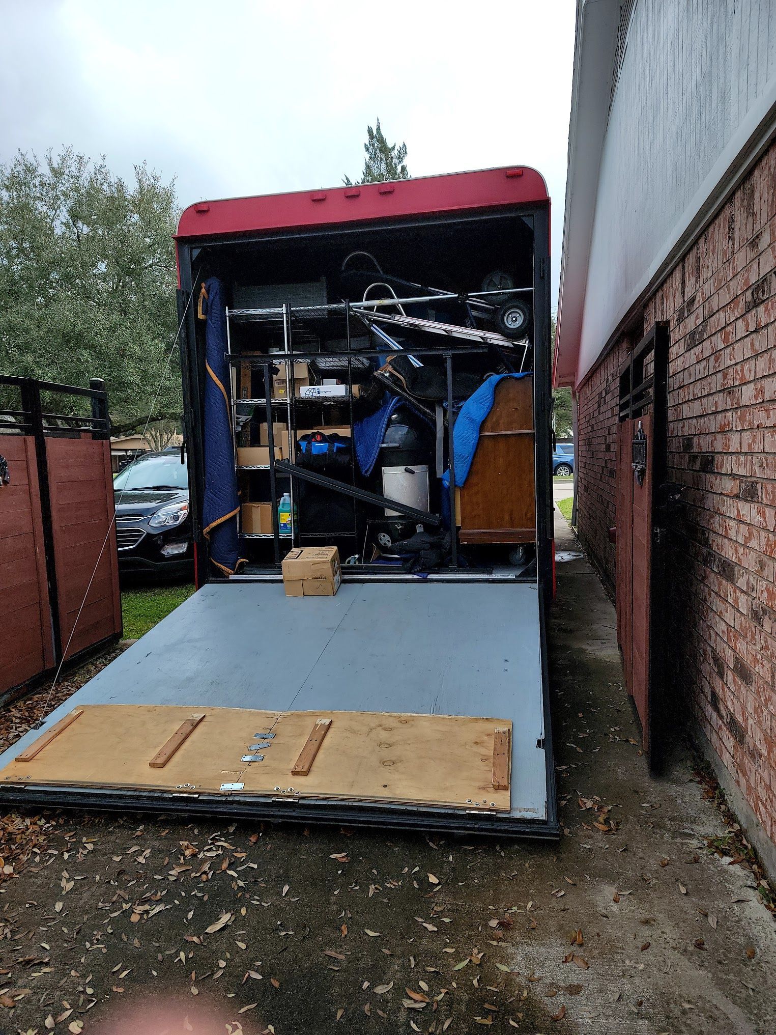 A moving truck filled with furniture and a bicycle is parked next to a brick building.