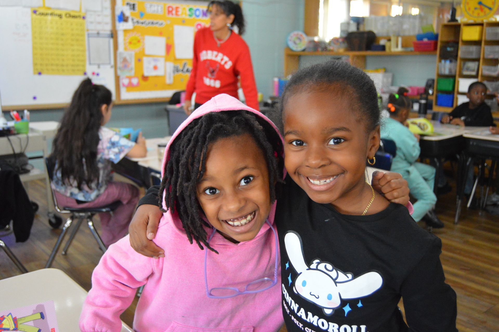 Two young girls smiling, arm in arm