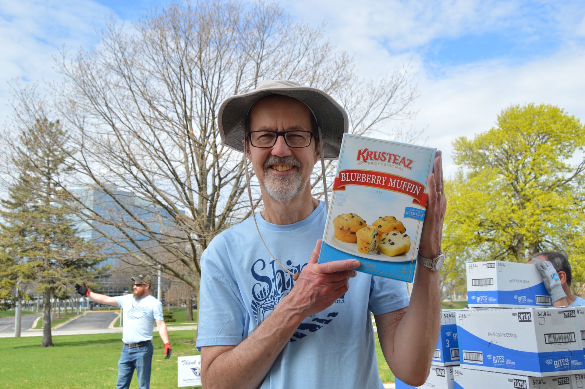 A man in a hat is holding a box of muffin mix.