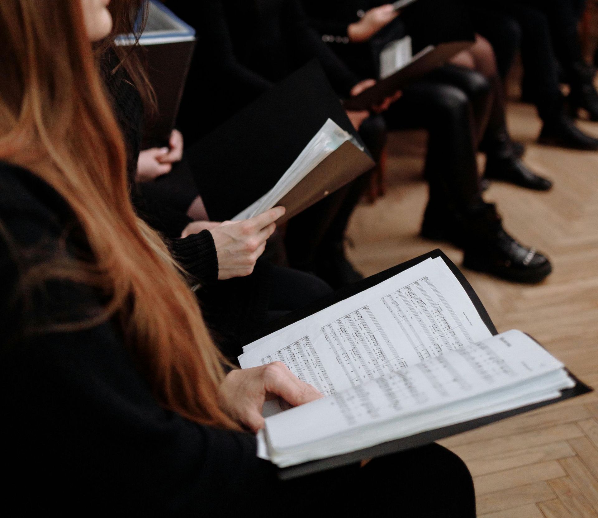 A woman is sitting in a chair reading music
