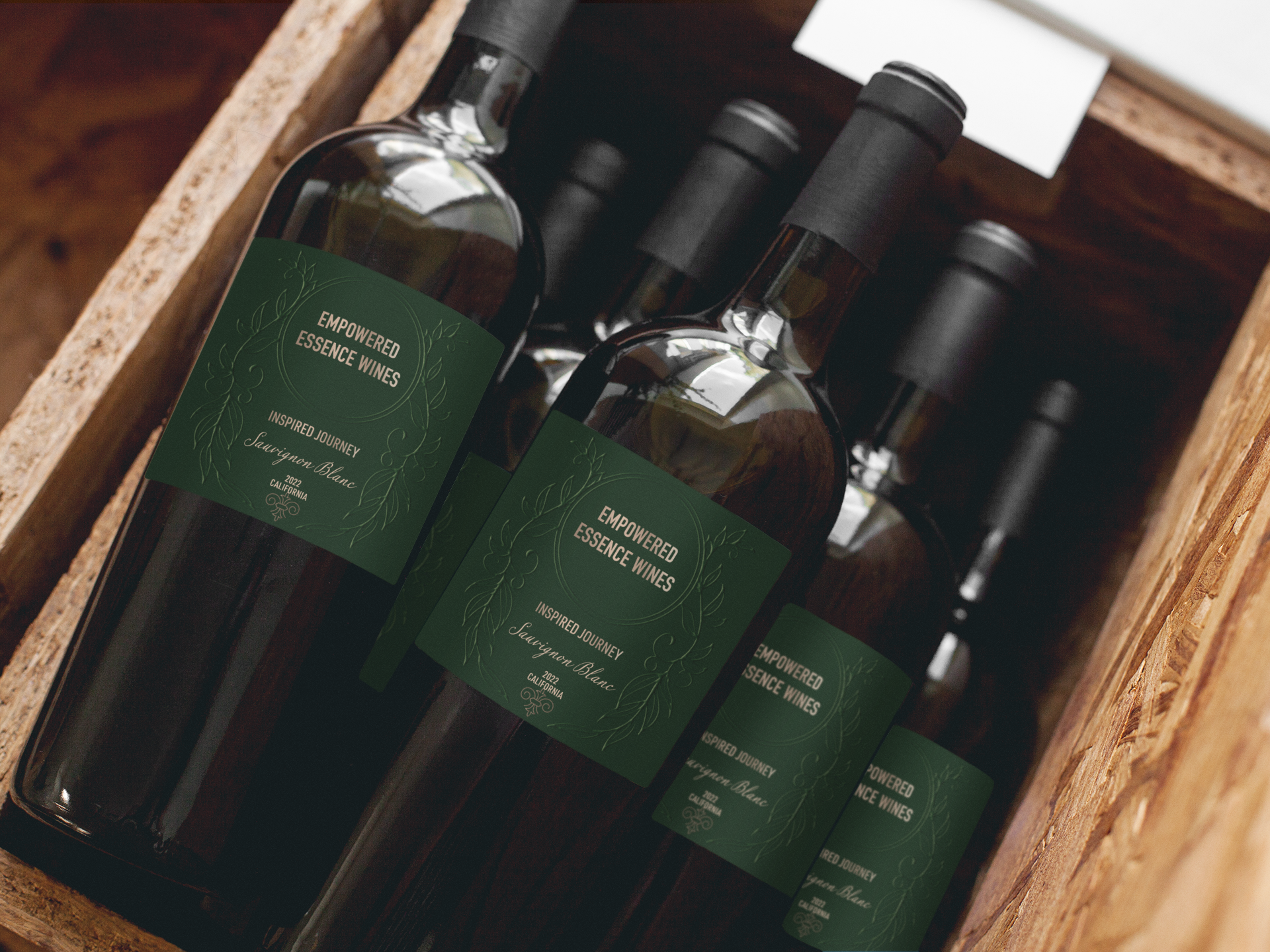Wine bottles in a wooden crate, dark green labels, black bottle tops.