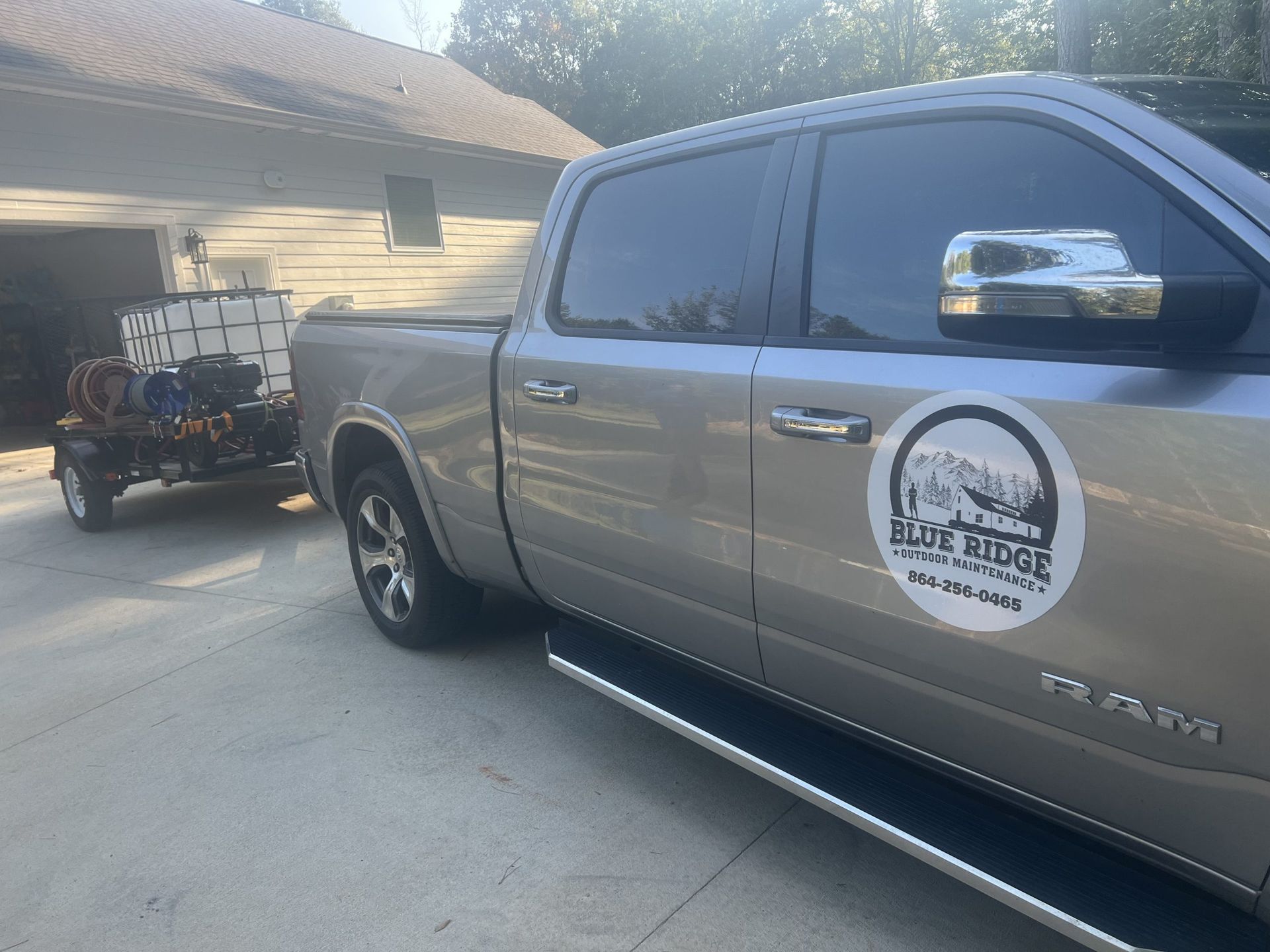 A silver Ram truck with Blue Ridge Lawn Care logo next to a trailer with spray equipment.