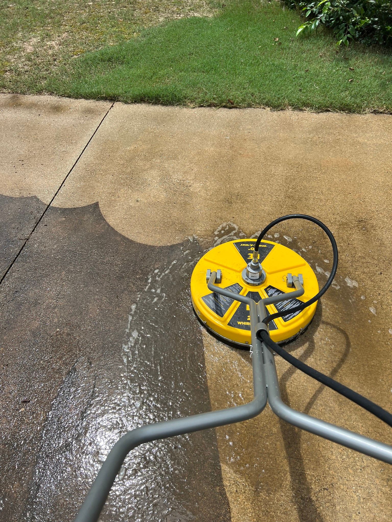 Yellow surface cleaner scrubbing a concrete surface, revealing clean area next to dirty.