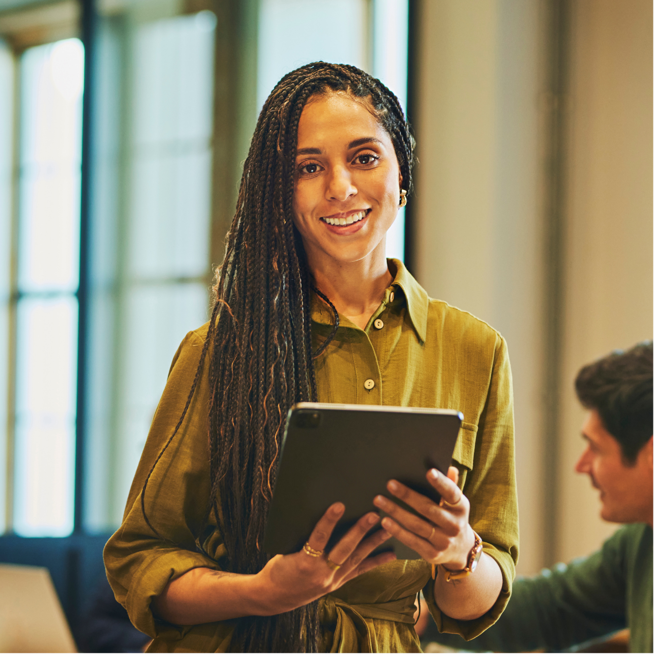 A woman is holding a tablet in her hands and smiling.