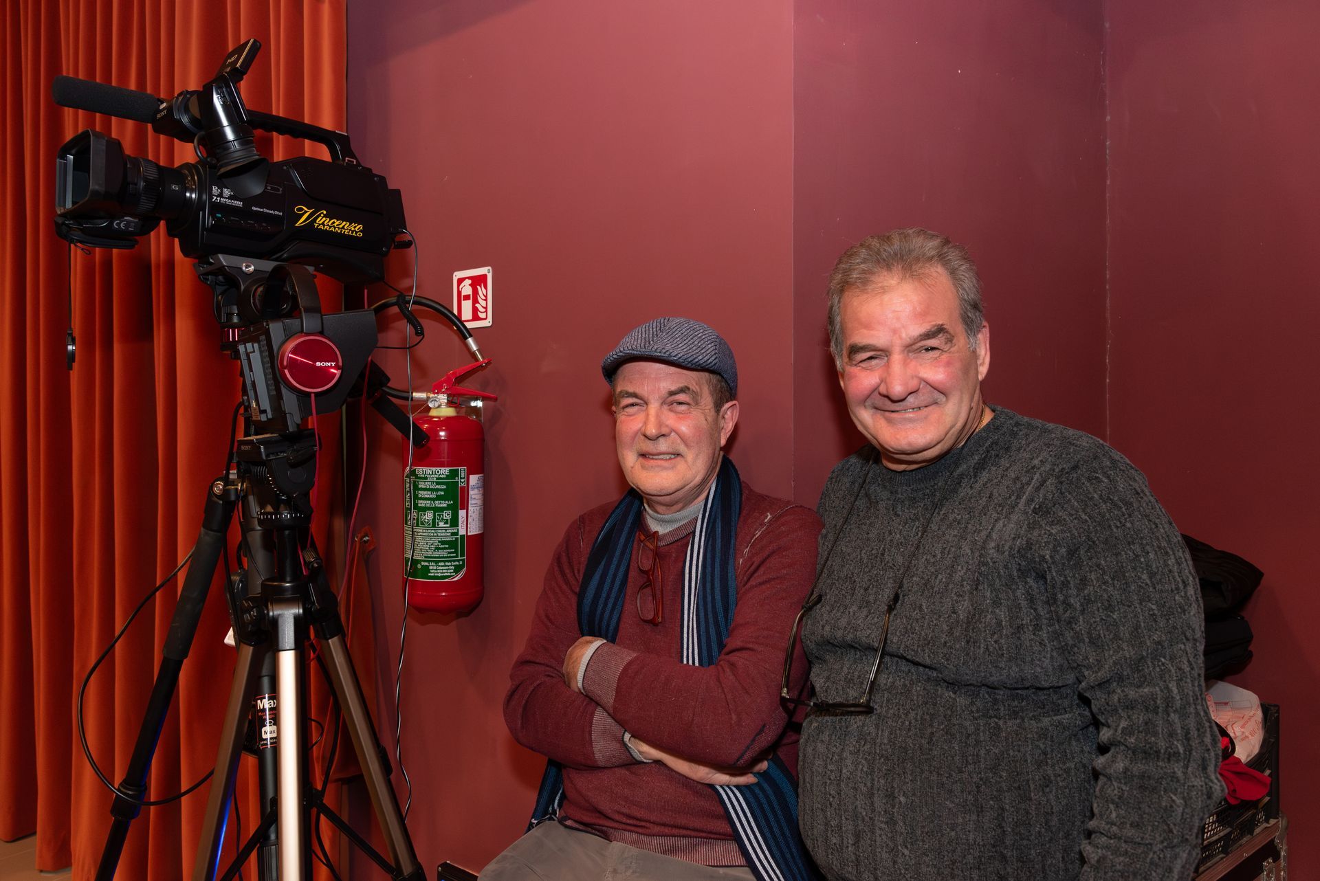 Due uomini sono in piedi uno accanto all'altro davanti a una telecamera.