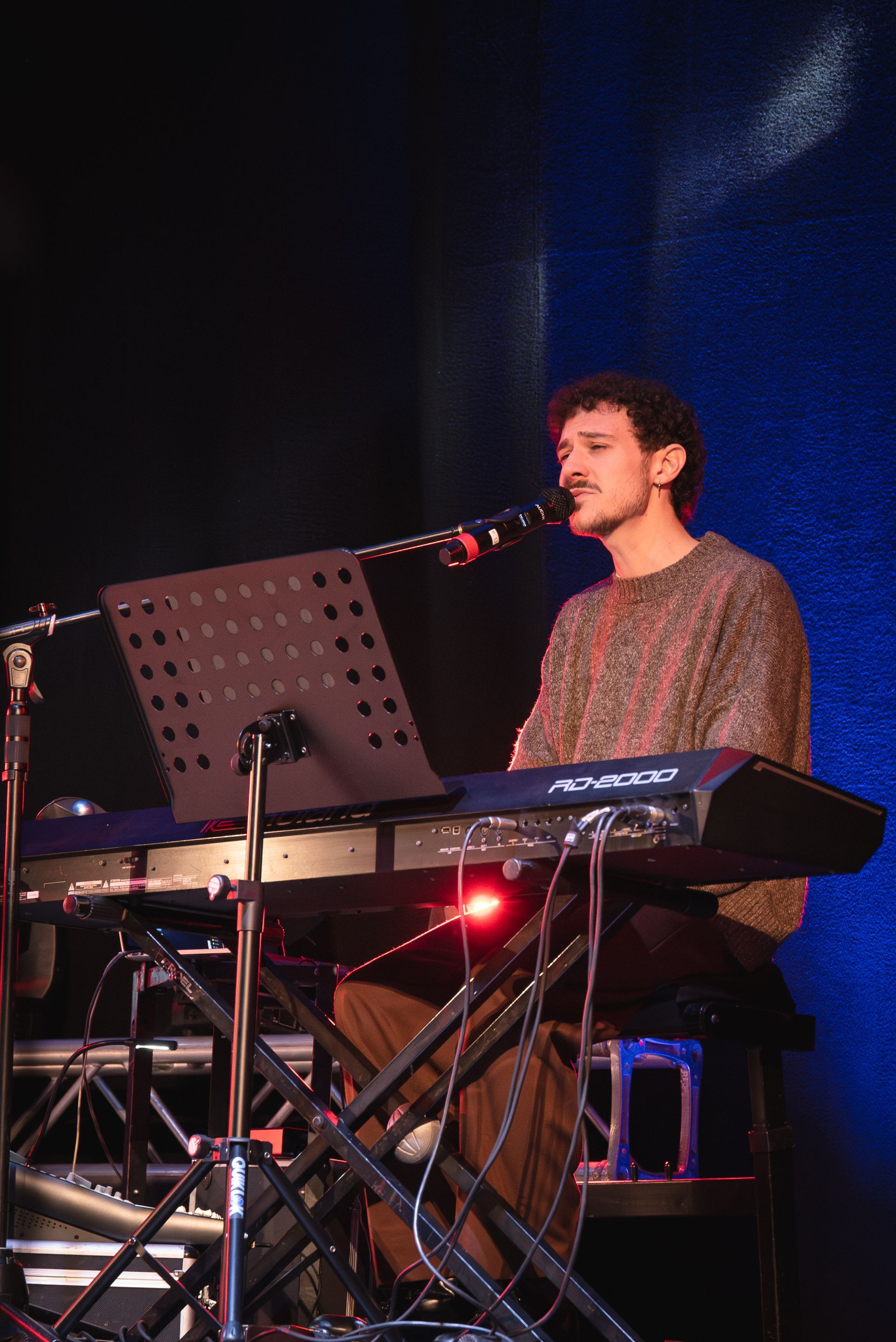 Un uomo canta in un microfono mentre suona una tastiera