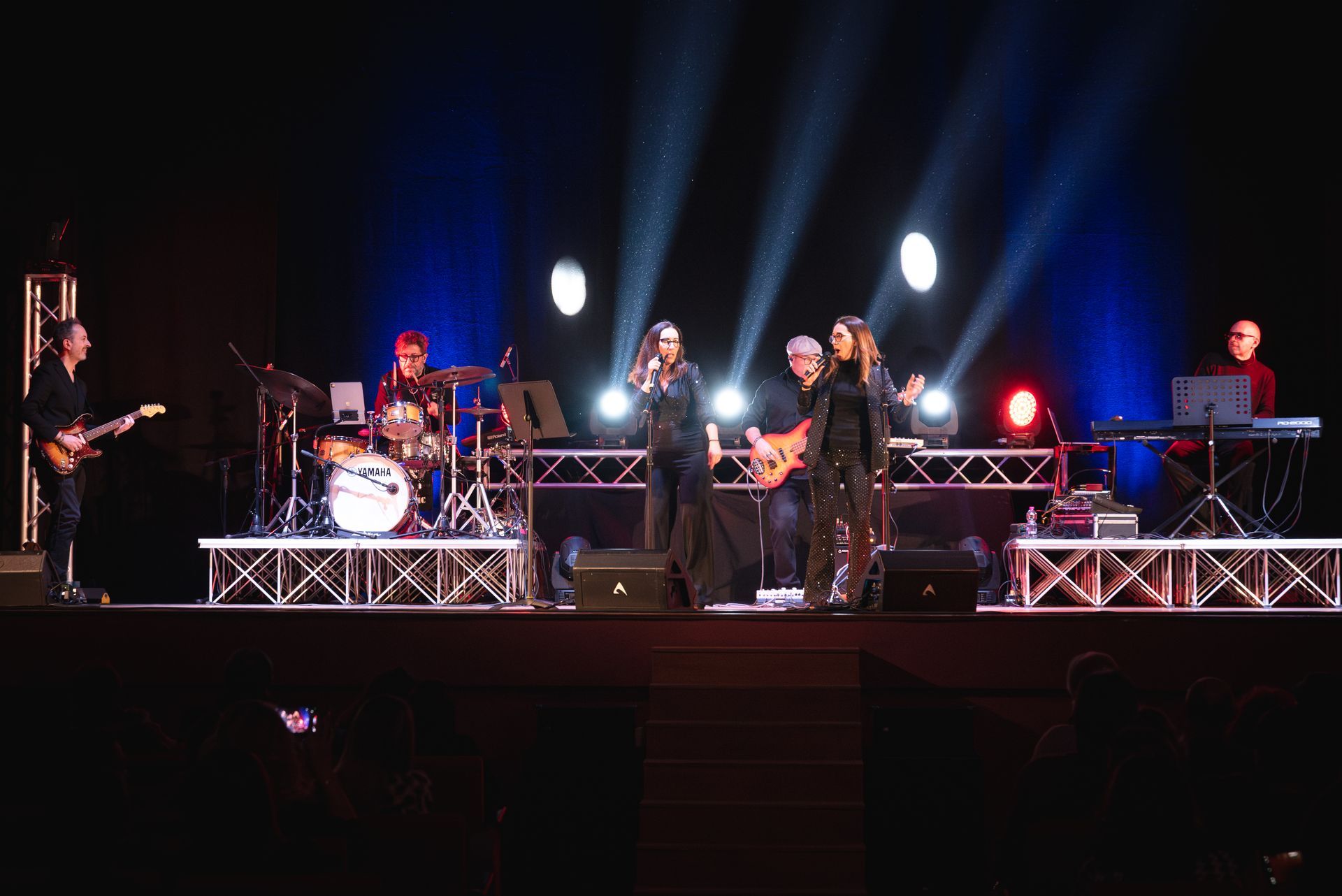 Un gruppo di persone è in piedi su un palco e suona degli strumenti.
