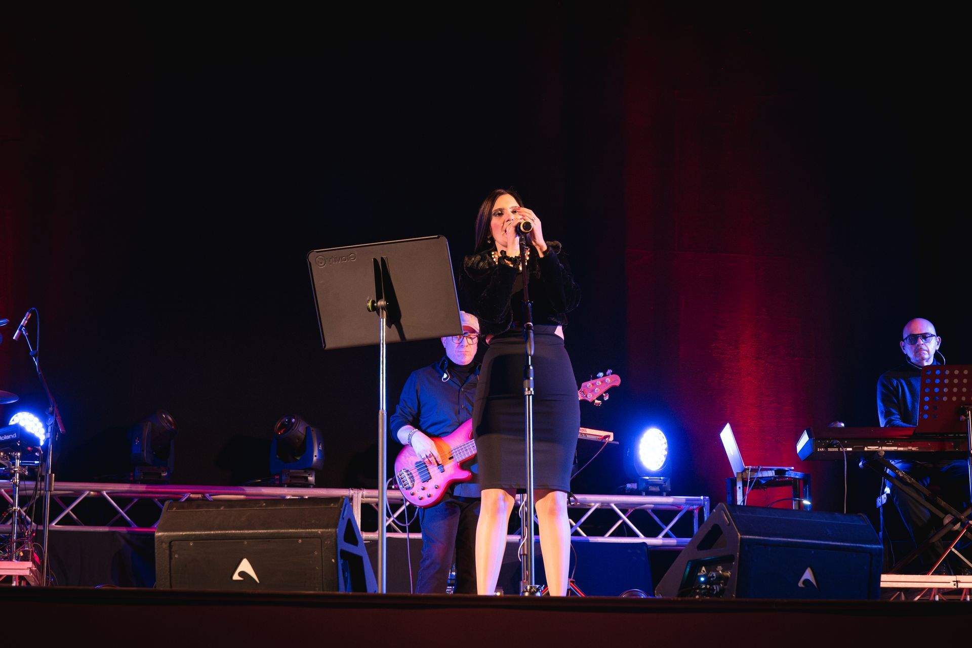 Una donna canta in un microfono su un palco mentre un uomo suona la chitarra.