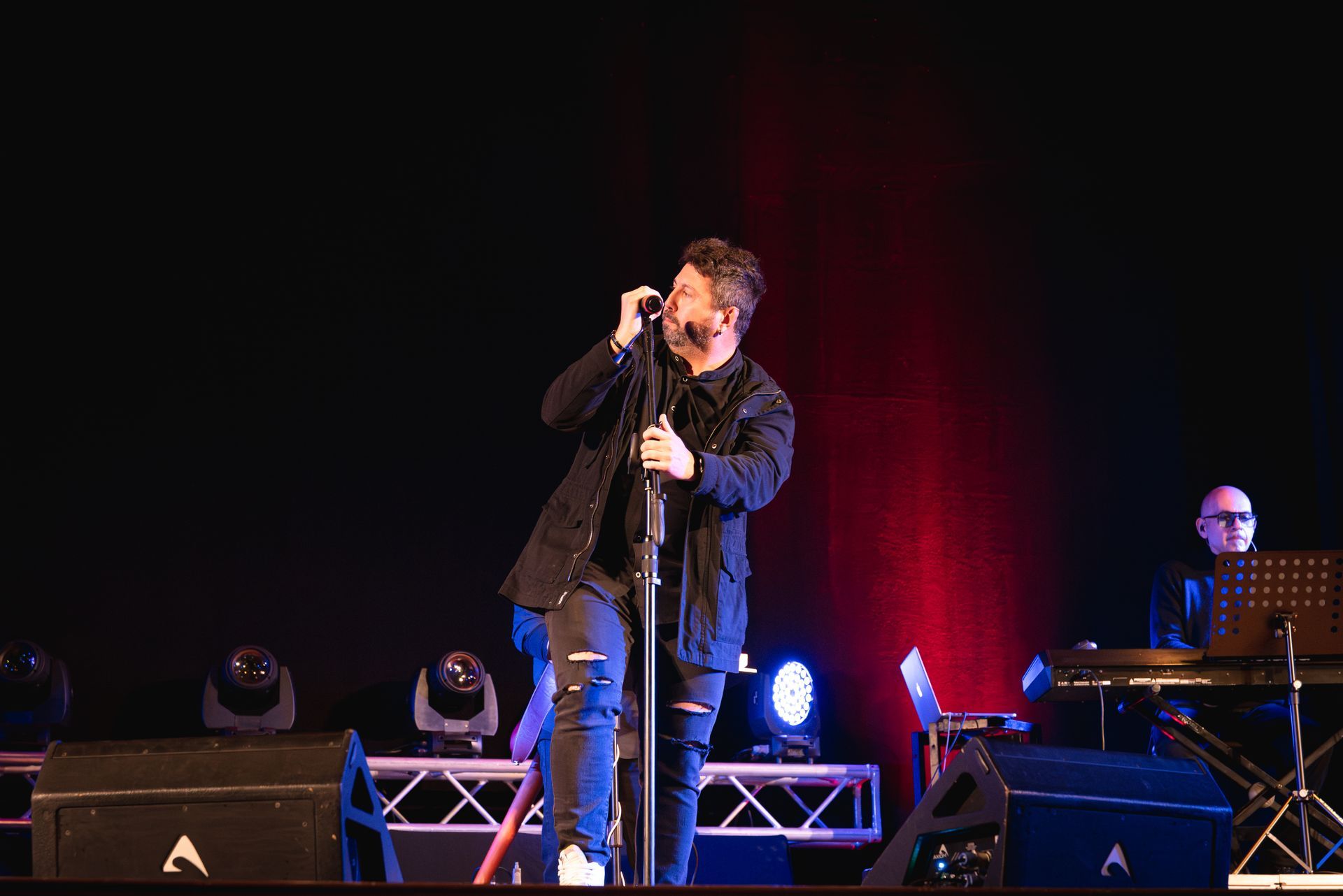 Un uomo canta in un microfono su un palco.