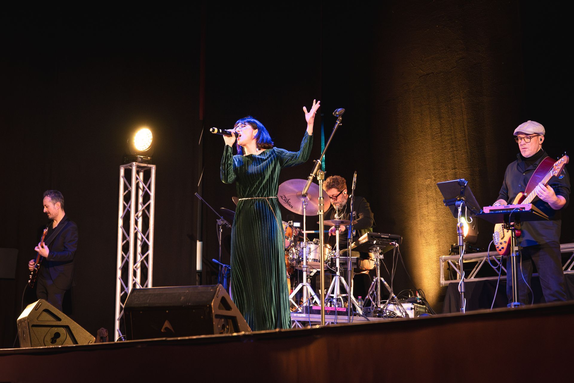 Una donna canta in un microfono su un palco con una band.