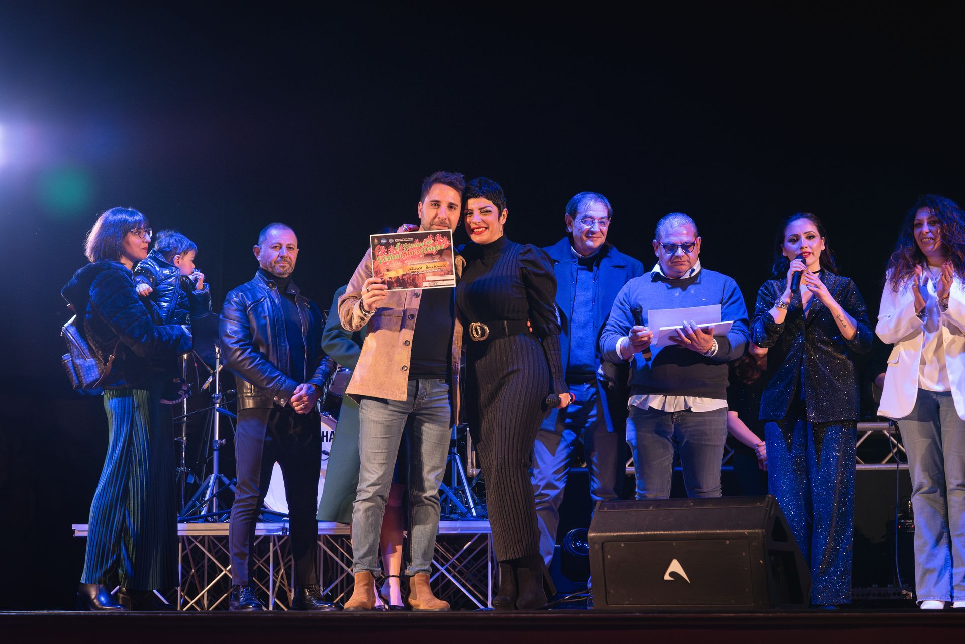 Un gruppo di persone è in piedi su un palco davanti a un microfono.