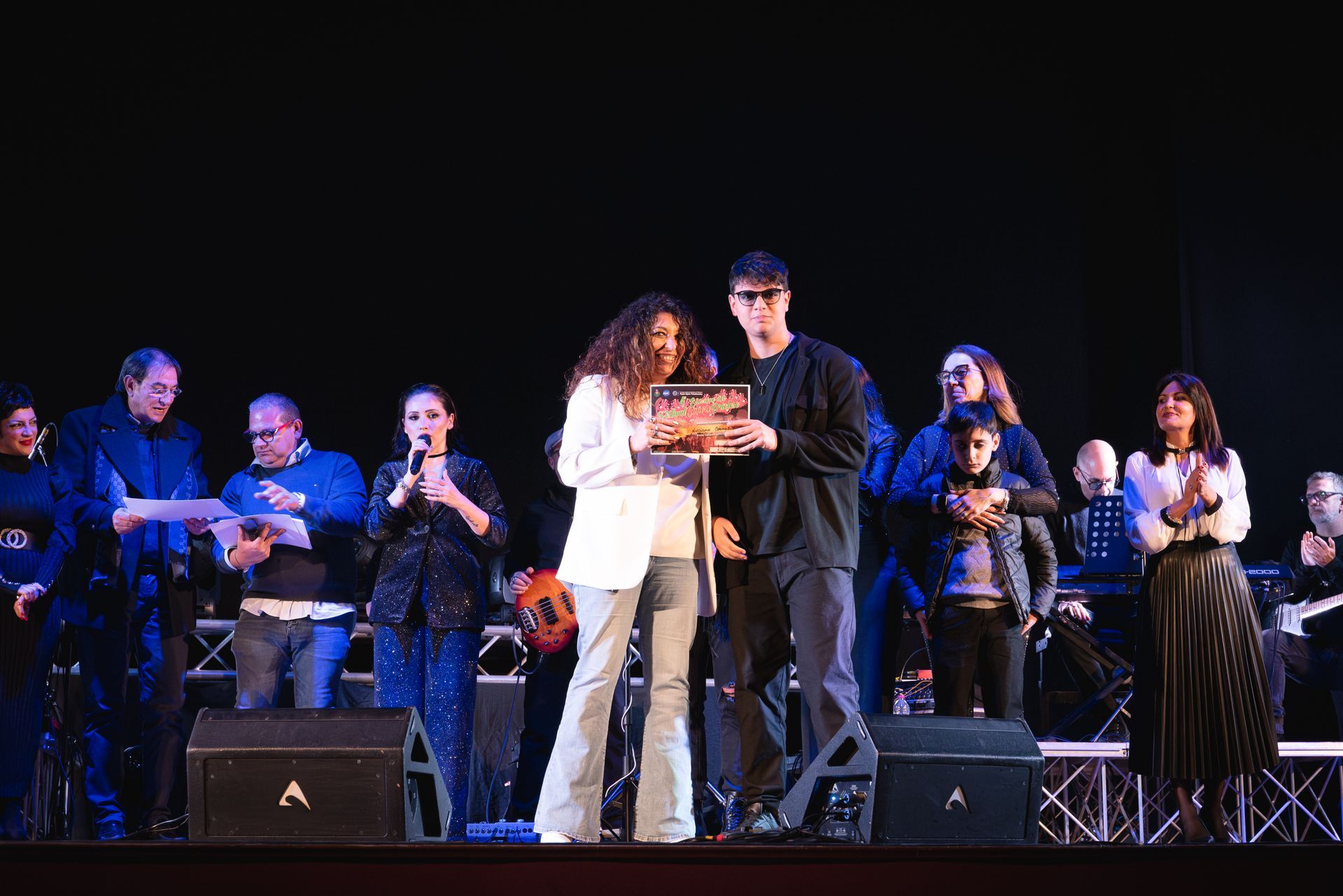 Un gruppo di persone è in piedi su un palco davanti a un microfono.