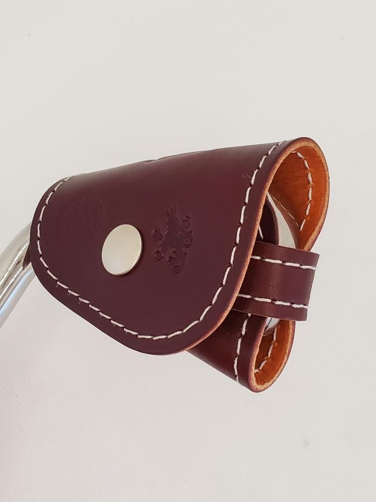 Mahogany leather ClubShield with white stitching and silver snap, attached to a club head.