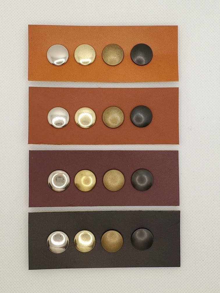 Four rectangular leather swatches, each with four different-colored metal rivets: silver, gold, bronze, and black.