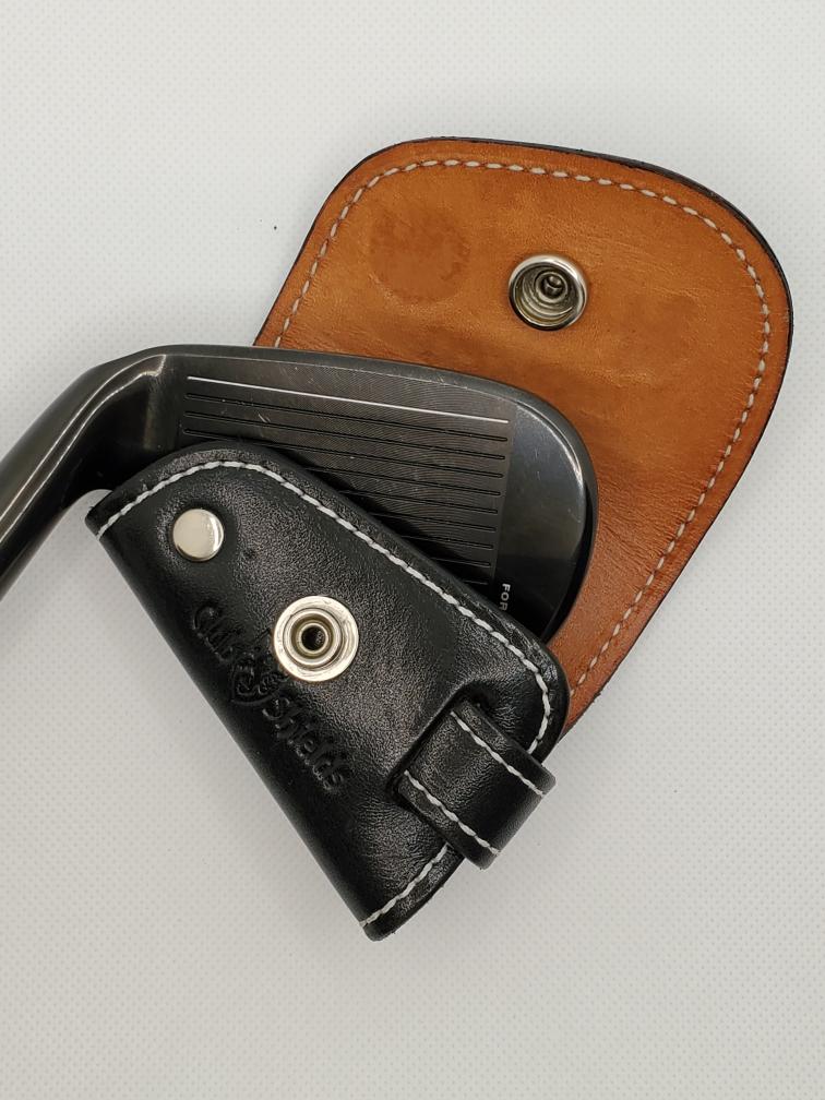 Black golf club with leather cover. Outer black and inner Tan on a light background.
